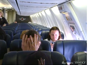 Man on flight covering face, looking scared